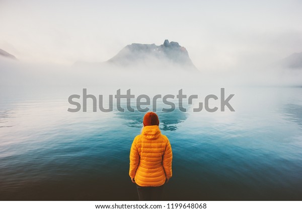 Woman alone looking at foggy sea\
traveling adventure lifestyle outdoor solitude sad emotions winter\
down jacket clothing cold scandinavian minimal\
landscape