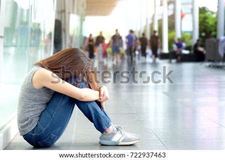 woman alone sitting in the corner strained unhappy depressed, destroyed, wasted and sad suffering .City and people background