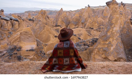 Woman alone with the volcanic landscape at Devrent Valley in Cappadocia. Girl walking around Fairy chimneys surronded by tufa formations at Imaginary Valley in winter season in Cappadocia, Turkey.
