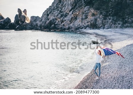 Woman with American flag on the beach. 4th of July. Independence Day. Patriotic holiday.