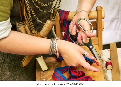 A Woman In Ancient Byzantine Clothing Makes Yarn And Sews From Vintage Fabric Threads. Reconstruction Of The Events Of The Middle Ages In Europe.