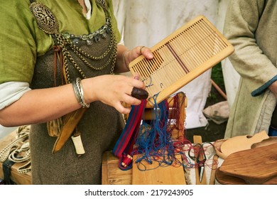 A Woman In Ancient Byzantine Clothing Makes Yarn And Sews From Vintage Fabric Threads. Reconstruction Of The Events Of The Middle Ages In Europe.