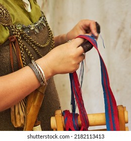 A Woman In Ancient Byzantine Clothing Makes Yarn And Sews From Vintage Fabric Threads. Reconstruction Of The Events Of The Middle Ages In Europe.