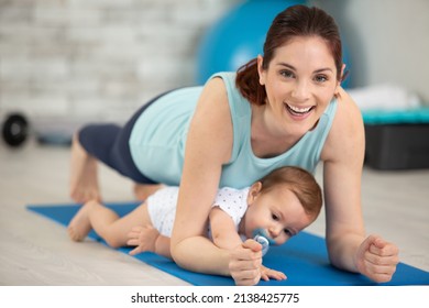 woman ane baby boy exercising on floor at home - Shutterstock ID 2138425775