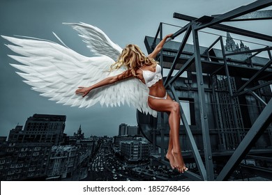 Woman Angel with Wings. Flying Girl. Angelic beautiful woman with wings stay on the roof of the house. Fashion photo in the style of fantasy.