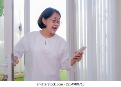 A woman answering a phone call while coming into the house.  - Shutterstock ID 2254980715