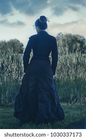 A Woman In Antique Clothes Near A Swamp