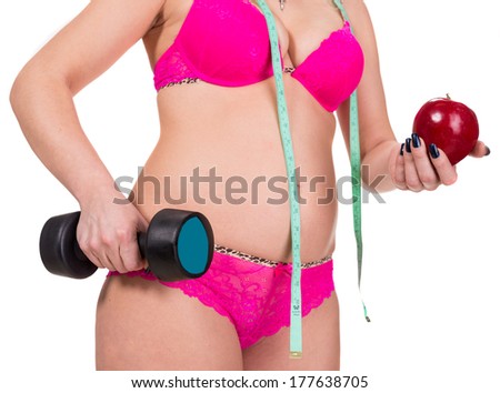 Woman with apple, dumpbell and  measuring tape on a white background.