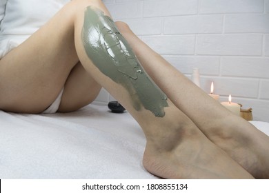 A woman applies a clay mask to the skin of her legs. Ingrown hairs. Irritation after depilation, shaving. Home skin care, body. SPA, moisturizing, treatment. Exfoliation, peeling. Strawberry legs.