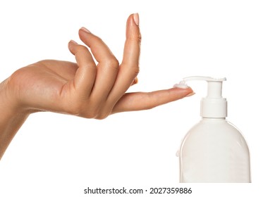 a woman applies a cosmetic product with a pump on her finger on a white background