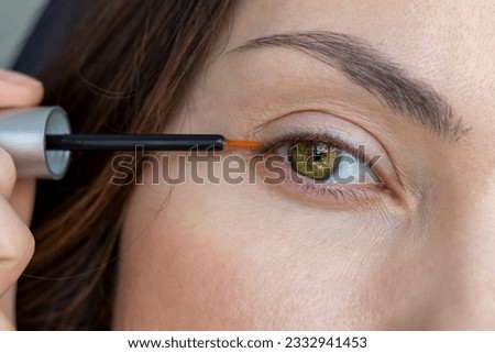 A woman applies eyelash growth product, close up