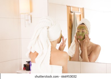 The Woman Applies Green Organic Face Mask In The Bathroom