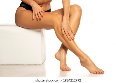 woman applies lotion on her beautiful legs on a white background