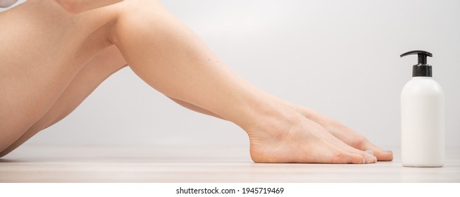 Woman applies moisturizer to her legs on white background. Widescreeen