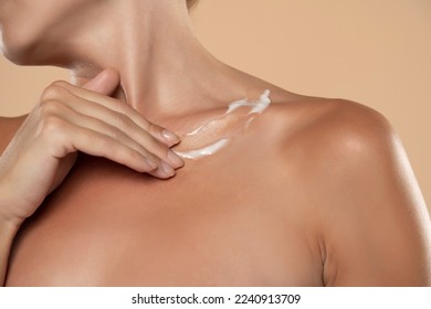 Woman apply body cream lotion on her chest on a beige studio background - Shutterstock ID 2240913709