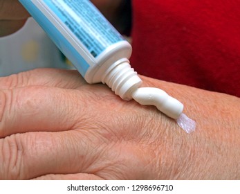 Woman apply medical ointment or cosmetic cream on hand from plastic tube close up