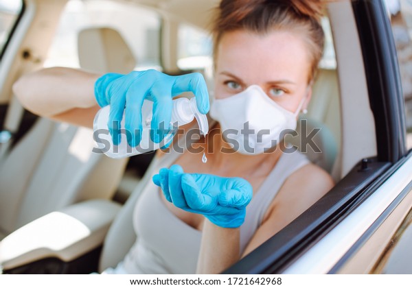 Woman\
applying alcohol gel for cleaning hands in gloves before using car\
in day time from escape Vocid or Corona\
virus.