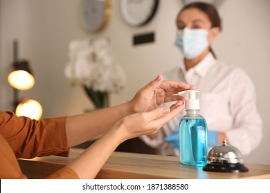 Woman Applying Antiseptic Gel At Hotel Reception, Closeup