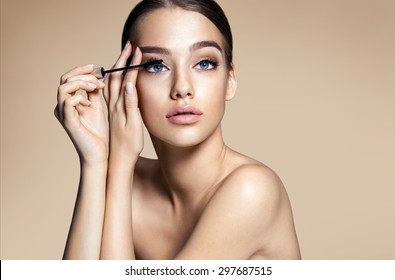 Woman Applying Black Mascara On Eyelashes With Makeup Brush  Photos Of Appealing Brunette Girl On Beige Background