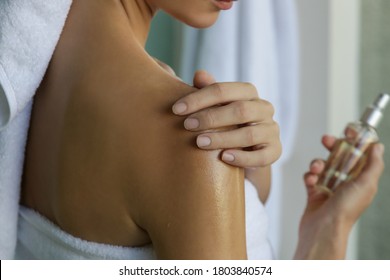 Woman applying body oil to moisturize her skin after shower, beauty skin care concept	