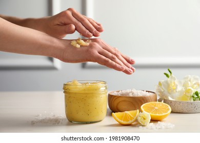 Woman Applying Body Scrub On Hand At Wooden Table, Closeup