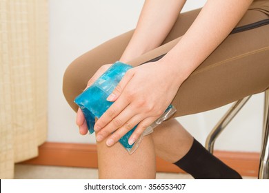 Woman Applying Cold Pack On Swollen Hurting Knee After Sport Injury