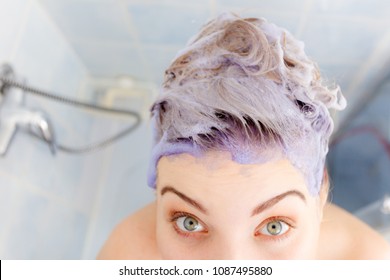 Woman Applying Coloring Shampoo On Her Hair. Female Having Purple Washing Product. Toning Blonde Color At Home.