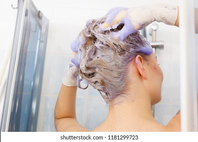 Woman Applying Coloring Shampoo On Her Hair. Female Having Purple Washing Product. Toning Blonde Color At Home.