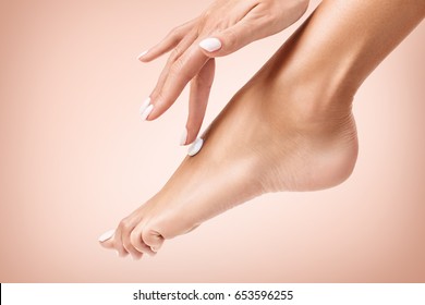 Woman Applying Cream On Her Beautiful Feet.