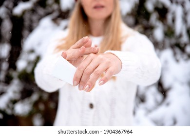 Woman Applying Cream On Skin Hands In Winter Season. Dry And Rough Skin Protection Treatment Outdoor. Hand Skin Care. Close Up Of Female Hands Applying Cream, Lotion.