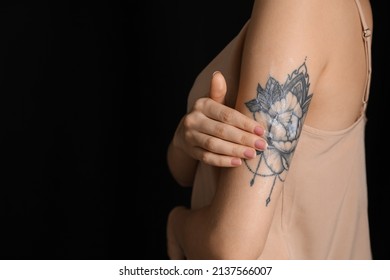 Woman Applying Cream Onto Her Arm With Tattoo On Dark Background, Closeup. Space For Text