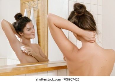 Woman applying deodorant  on her armpit