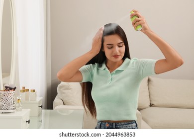 Woman Applying Dry Shampoo Onto Her Hair At Home