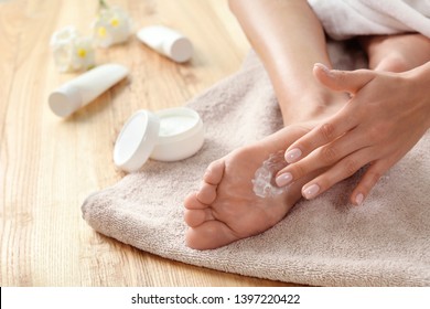 Woman Applying Foot Cream On Towel, Closeup. Spa Treatment