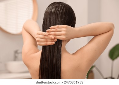 Woman applying hair mask in bathroom, back view - Powered by Shutterstock