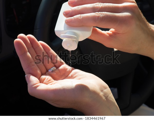 Woman applying\
hand sanitizer gel for coronavirus prevention. Focus on\
disinfectant bottle. Senior Hispanic woman with face mask driving\
her car. Covid-19 (Corona virus)\
concept.