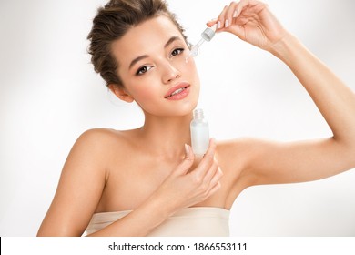 Woman Applying  Hyaluronic Serum On Her Face With Pipette. Photo Of Attractive Woman With Perfect Makeup On White Background. Beauty Concept