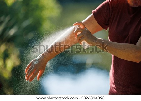 Woman applying insect repellent on her arm outdoors. Skin protection against tick and mosquito bite