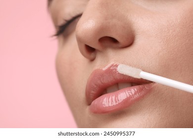 Woman applying lip gloss on pink background, closeup. Space for text - Powered by Shutterstock