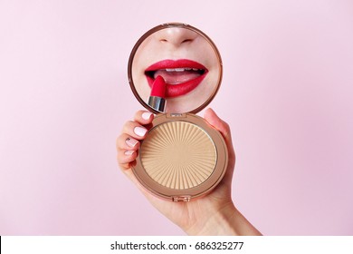 Woman Applying Lipstick Looking At Mirror In Hand. Red Lips Makeup Closeup.