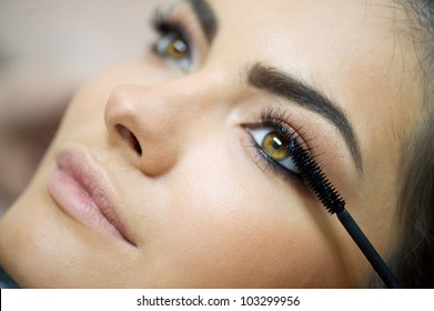 Woman applying mascara on her long eyelashes