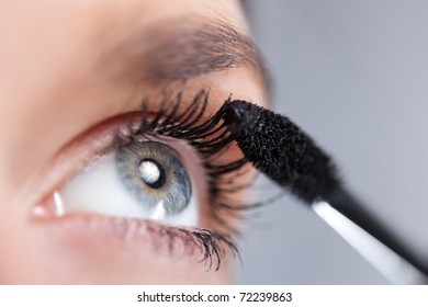 Woman Applying Mascara On Her Eyelashes. Short Depth Of Field