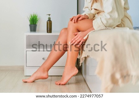 Woman applying moisturizer cream to her feet after shower. Bodycare