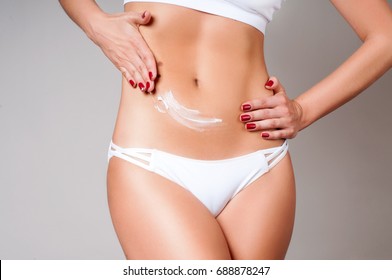 Woman applying moisturizer cream lotion on belly. Getting rid of belly fat and weight loss. Young woman wear white underwear