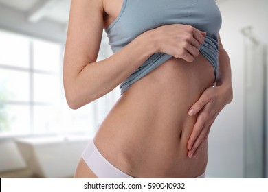 Woman applying moisturizer cream on her body, beauty and skin care concept. Healthy woman body, waistline. Slim female torso, belly, abdomen close up. Sport, fitness, Dieting results.