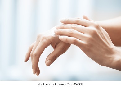 Woman applying moisturizing cream on hands