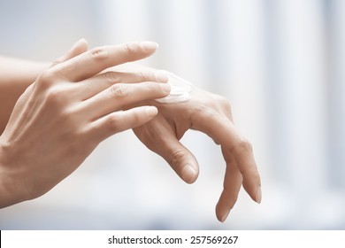 Woman applying moisturizing cream on hands