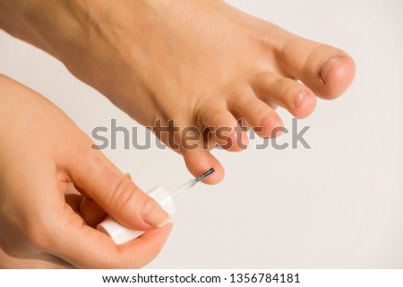 woman applying a nail polish on her toes