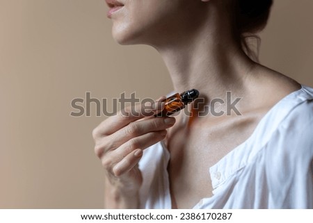 Woman applying natural rollerball aroma oil on her neck close up	
