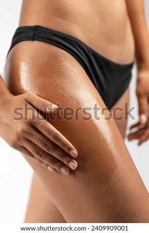 Woman applying oil cosmetics on her skin on her thigh